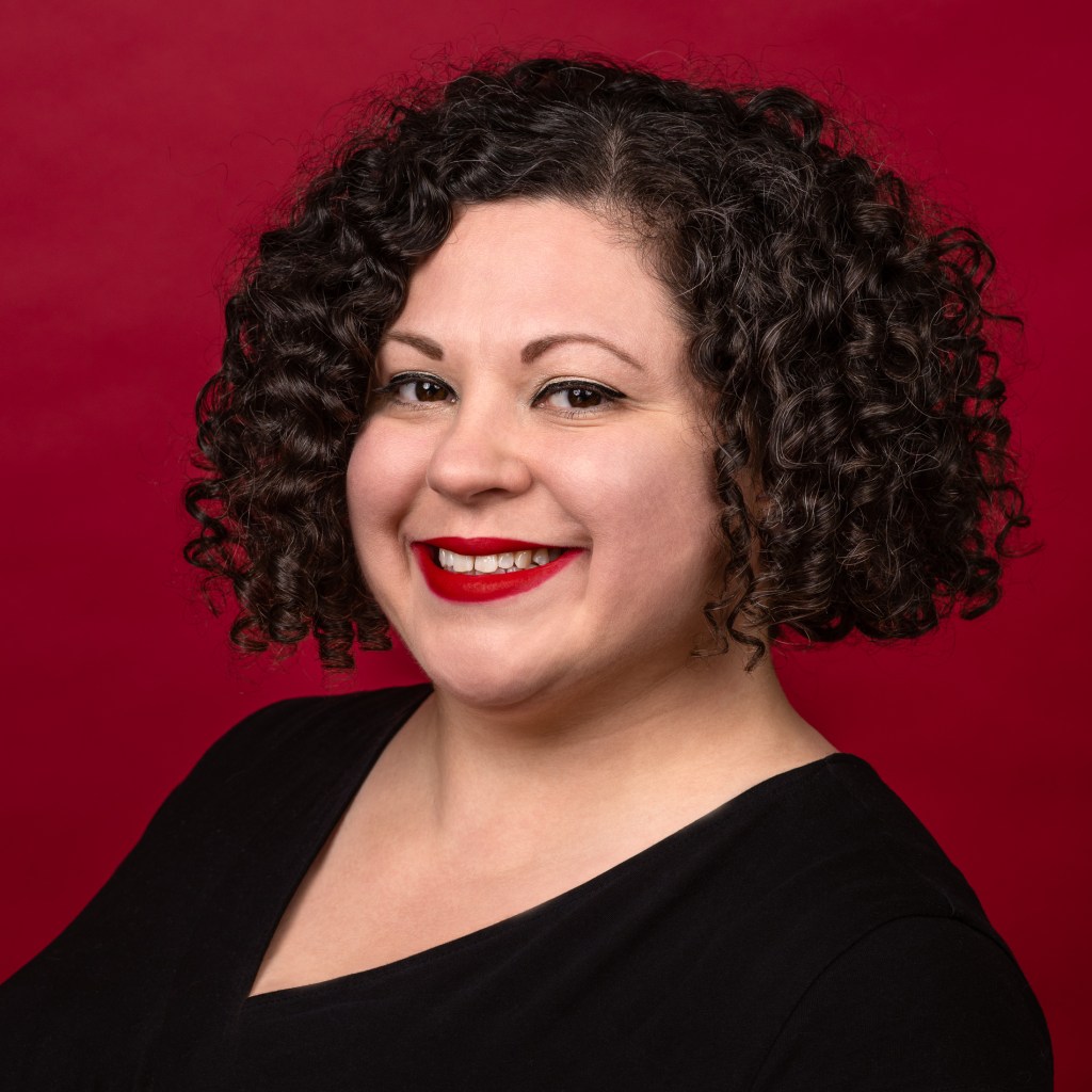Anita Mechler headshot in front of dark red background